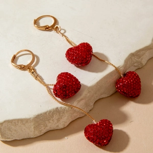 Detailed macro view of long drop earrings with sparkling red rhinestone heart pendants