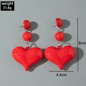 Detail view of large red resin heart earrings with 8cm length and polished finish