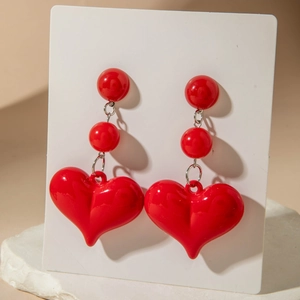 Detail of red tiered heart earrings featuring glossy beads and silver metal connectors