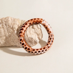 Detailed view of elastic leopard print acrylic tube bracelet on a neutral stone display