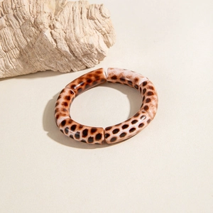 Detail of leopard print acrylic tube beads with a glossy finish on an elastic bracelet