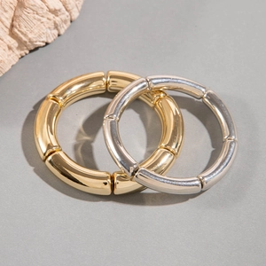 Macro shot of interlocking gold and silver polished metal curved tube bracelets