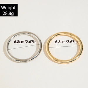 Macro detail of gold and silver curved tube bracelets showing 6.8cm inner diameter