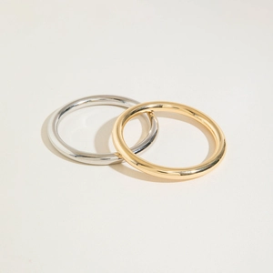 Detail of minimalist minimalist gold and silver polished metal rings on beige background