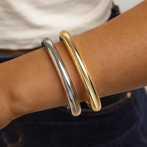 Close-up of minimalist chunky C-shaped open bangles in polished gold and silver finish