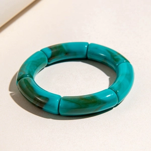 Top view of turquoise marble acrylic bracelet with curved resin links on white surface