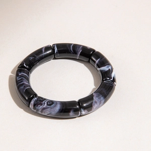 Detail view of monochrome marble resin bracelet with curved segments and glossy finish