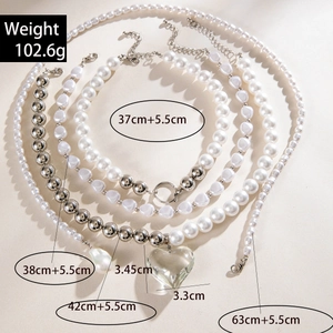 Détail d'un ensemble de colliers avec perles d'imitation et pendentif cœur argenté