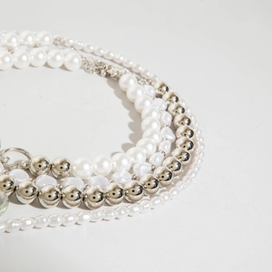 Détail d'un collier multicouche avec perles baroques et billes en métal argenté poli