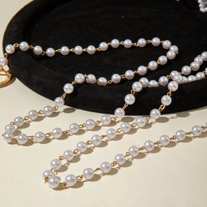 Détail d'un collier de perles multicouche avec perles blanches et maillons dorés