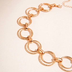 Detail of double-layer gold metal necklace featuring hammered and polished square rings