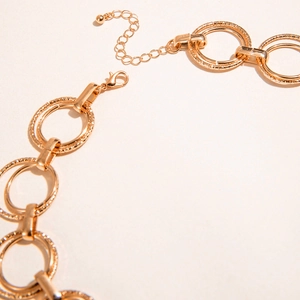 Double-layered gold circular ring necklace with intricate floral engraving and adjustable chain