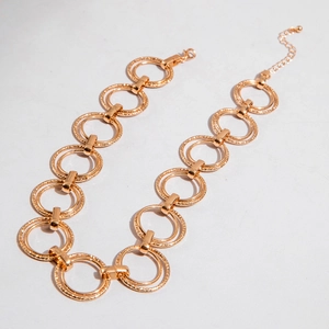 Macro detail of gold chunky double-circle chain link necklace with hammered texture finish