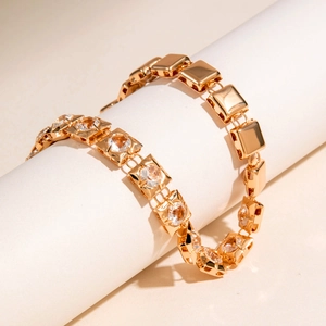 Macro detail of gold-plated square chain links with sparkling round zirconia insets