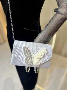 Détail d'une pochette de soirée en satin plissé argenté avec papillon en strass et fleurs