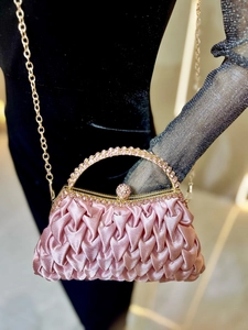 Macro detail of pink satin pleated clutch bag with shimmering rhinestone handle