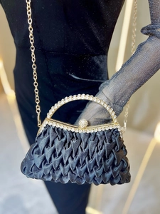 Detail of black satin evening clutch with rhinestones, metal chain and pleated texture
