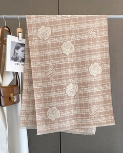 Detail of pink cashmere scarf with white rose print and tassels on a clothing hanger