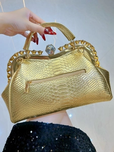 Detail of gold snake-skin evening bag with crystal clasp and metallic handle