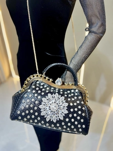 Detail of luxury black snake-embossed dinner bag with sun flower crystal decoration