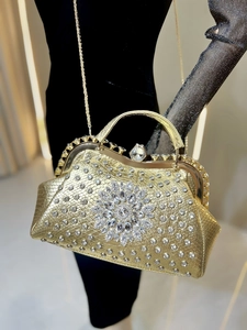 Close-up of golden evening handbag featuring luxury rhinestone flower and metal handle