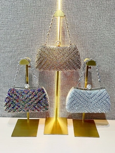 Detailed display of three luxury rhinestone evening clutch bags on elegant metal stands