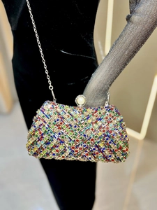 Close-up of colorful rhinestone evening clutch with pearl metal clasp and silver chain strap