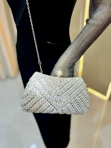 Close-up of luxury silver rhinestone evening clutch with large pearl clasp and chain strap