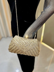 Detail of gold evening clutch with clear rhinestones, pearl clasp, and metal chain