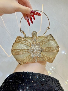 Macro shot of gold bow clutch bag featuring star-shaped rhinestones and metal handle