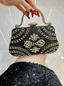 Detailed close-up of a luxury black rhinestone evening clutch with gold metal handle