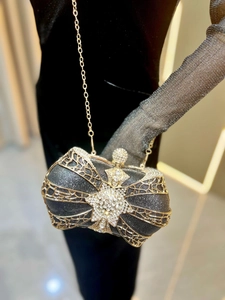 Detail of elegant black bow clutch bag with golden metal frame and sparkling rhinestones