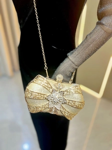 Luxurious gold bow-shaped clutch with glitter finish and rhinestone star detail