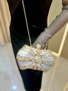 Detail of luxury bow-shaped evening clutch with gold lattice and sparkling crystals