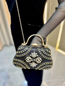 Detail of luxury rhinestones on evening bag with gold metal handle and velvet texture