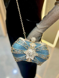 Detail of luxury peacock blue evening clutch with golden cage and rhinestone star