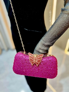 Detalle del bolso de fiesta fucsia con cristales y elegante cierre de mariposa dorada