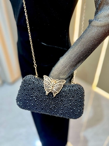 Detalle macro del bolso de noche de cristal negro con cierre de mariposa dorado