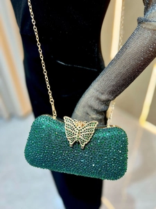 Primer plano de bolso de fiesta de strass verde esmeralda con elegante cierre de mariposa