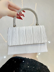Detail of silver evening bag with pleated satin and rhinestone-encrusted round handle