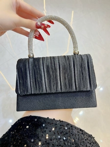 Detail of black pleated satin evening bag featuring a rhinestone-studded circular handle