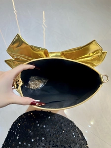 Fashionable gold bow-shaped clutch handbag with metallic finish and metal chain strap