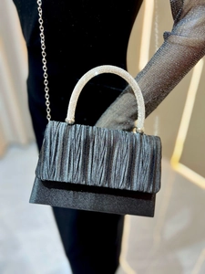 Detail of black pleated evening bag with sparkling rhinestone handle and silver chain