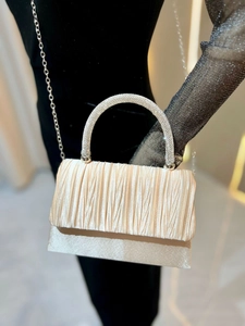 Detail of champagne pleated evening bag with rhinestone handle and silver chain strap