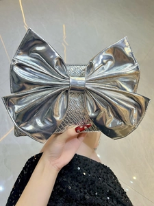 Close-up of a silver bow-knot evening clutch bag with detailed woven leather texture