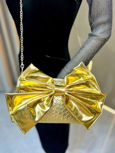 Close-up of golden evening clutch featuring giant bow design and crocodile texture