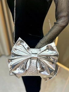 Detail shot of silver bow evening bag with woven texture and elegant metal chain strap