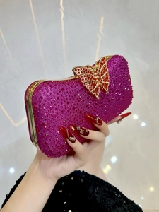 Elegante bolso de noche fucsia con pedrería, cierre de mariposa dorado y cadena al hombro