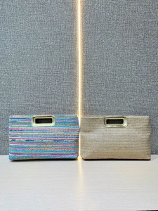 Straw clutch bag with gold metal handle and colorful stripes for shoulder or crossbody use