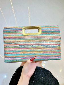 Detail of colorful striped straw clutch bag with gold-tone metallic handle for women